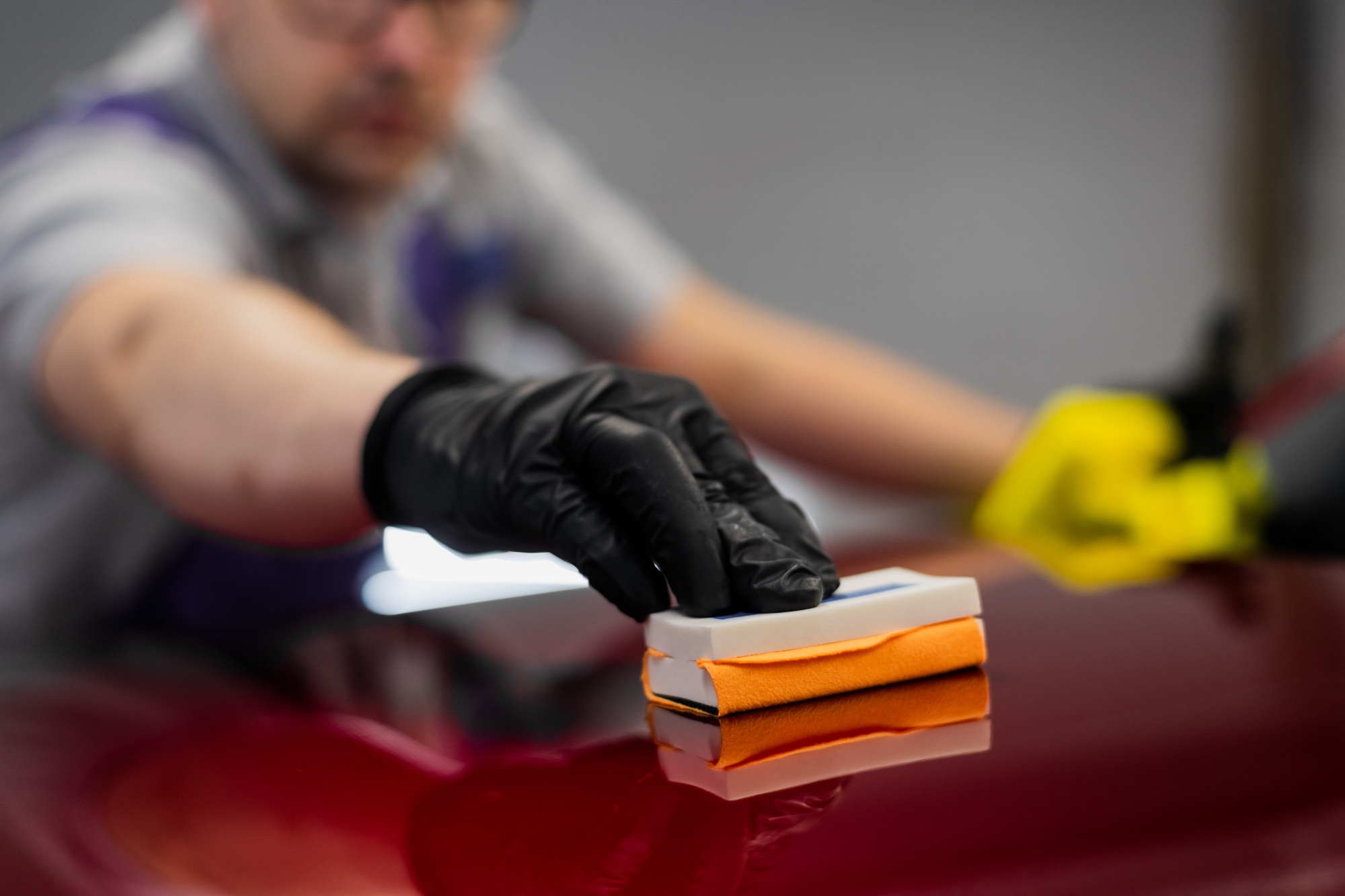 Close-up man applying ceramic coating on the red car at detailing service